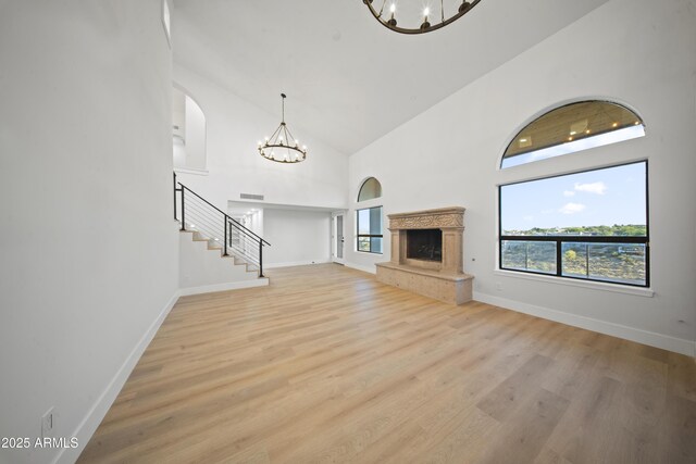 15641 E Sycamore Dr, Fountain Hills, AZ 85268 - unfurnished living room with a chandelier, high vaulted ceiling, stairs, and light wood-style flooring