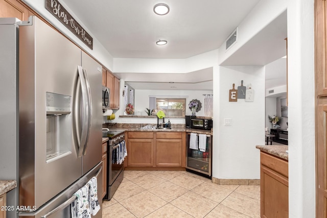 kitchen featuring sink, stone counters, stainless steel appliances, wine cooler, and light tile patterned flooring