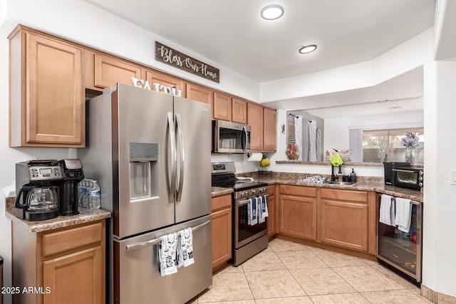 kitchen featuring wine cooler, light tile patterned floors, light stone countertops, and appliances with stainless steel finishes