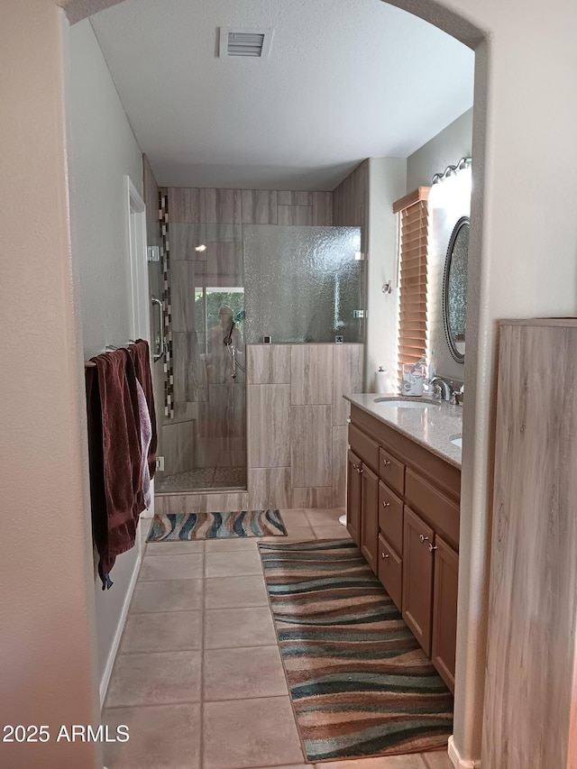 bathroom featuring vanity, tile patterned flooring, a wealth of natural light, and tiled shower