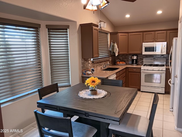 kitchen with white appliances, lofted ceiling, decorative backsplash, sink, and light tile patterned floors