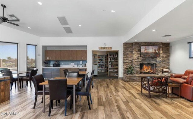 dining room featuring light hardwood / wood-style floors, ceiling fan, and a fireplace