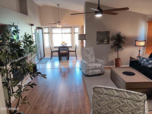 living room with ceiling fan, light hardwood / wood-style flooring, and vaulted ceiling