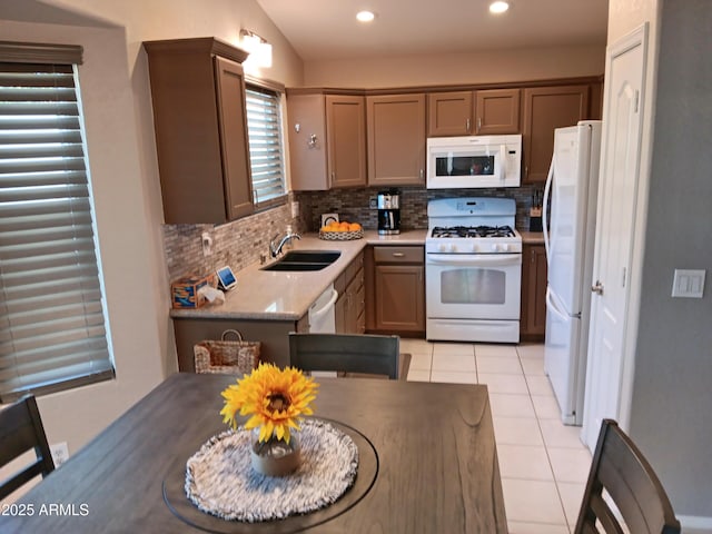 kitchen featuring light tile patterned floors, decorative backsplash, white appliances, light stone counters, and sink