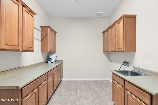 washroom featuring hookup for a washing machine, sink, light tile patterned floors, and cabinets