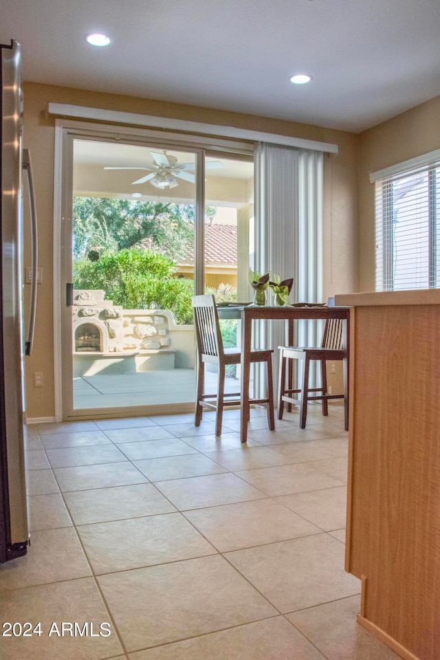 doorway with a healthy amount of sunlight, light tile patterned floors, and ceiling fan