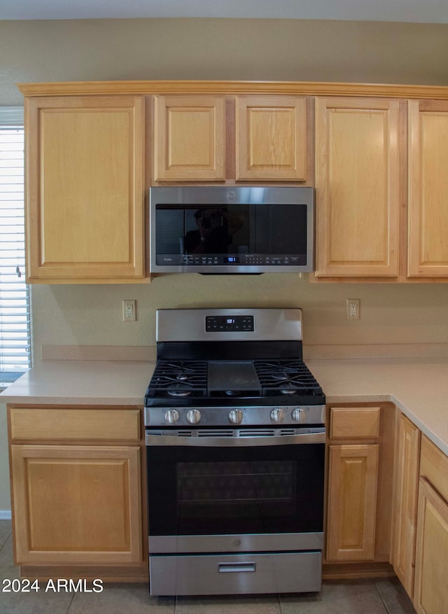 kitchen featuring light brown cabinets, stainless steel appliances, and light tile patterned floors