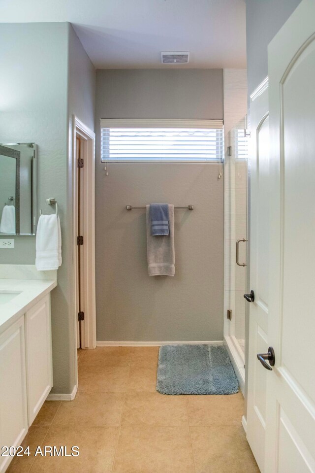 bathroom featuring vanity, tile patterned flooring, a shower with shower door, and a healthy amount of sunlight