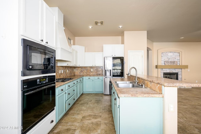 kitchen featuring sink, blue cabinets, an island with sink, white cabinets, and black appliances