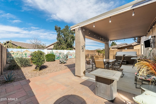 view of patio featuring outdoor dining area, a fenced backyard, and a hot tub