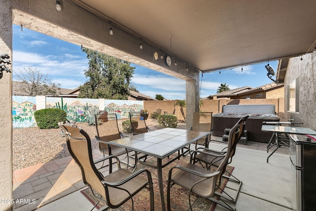 view of patio featuring outdoor dining area, a fenced backyard, and a hot tub