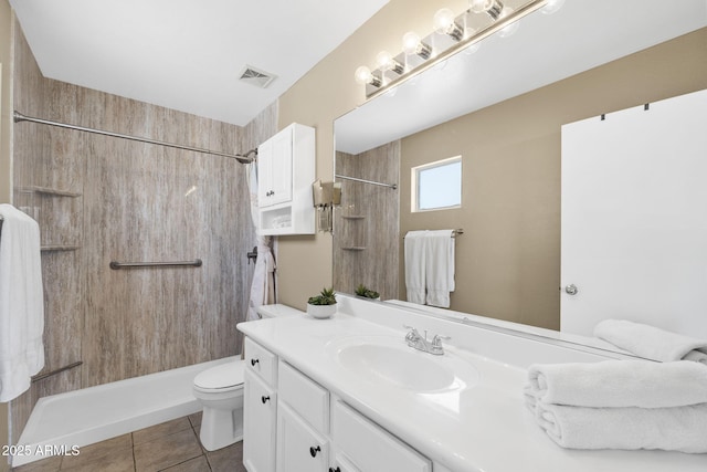 bathroom with tile patterned flooring, toilet, vanity, visible vents, and tiled shower