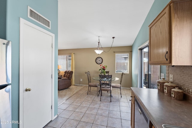 dining room with light tile patterned floors, vaulted ceiling, visible vents, and baseboards