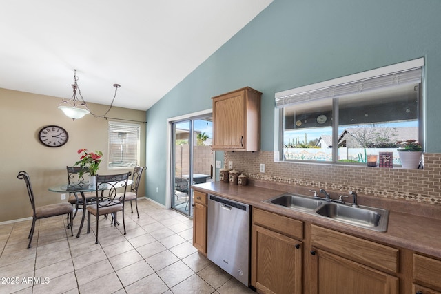 kitchen with tasteful backsplash, dark countertops, hanging light fixtures, a sink, and dishwasher