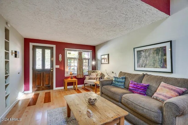 living area featuring a textured ceiling, baseboards, and light wood-type flooring