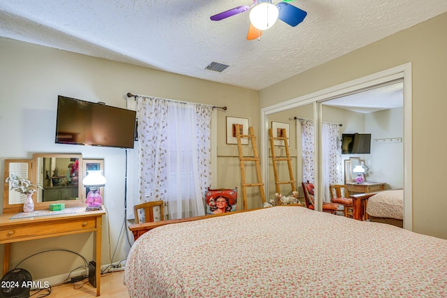 bedroom with a ceiling fan, a closet, a textured ceiling, visible vents, and wood finished floors