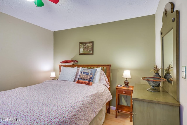 bedroom featuring light wood-style floors, ceiling fan, and a textured ceiling
