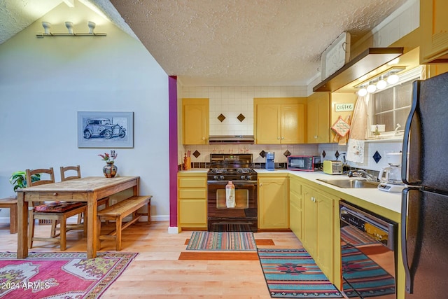 kitchen featuring a textured ceiling, light wood finished floors, a sink, black appliances, and light countertops