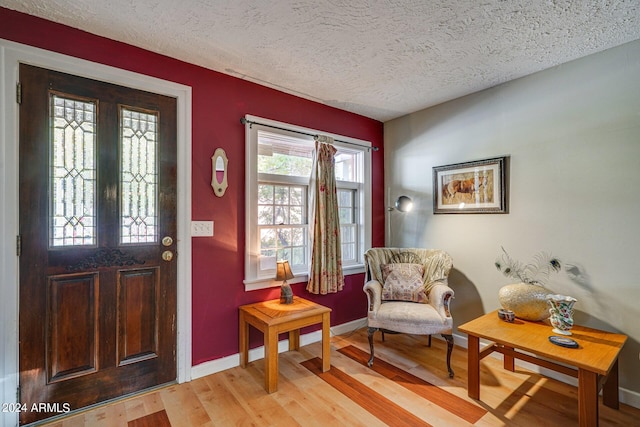 entryway featuring baseboards, light wood-style floors, and a textured ceiling