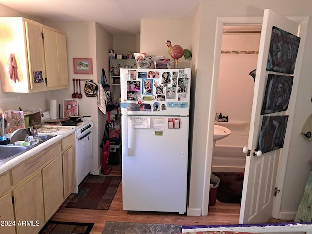 kitchen featuring light wood-style flooring, a sink, light brown cabinets, white appliances, and light countertops