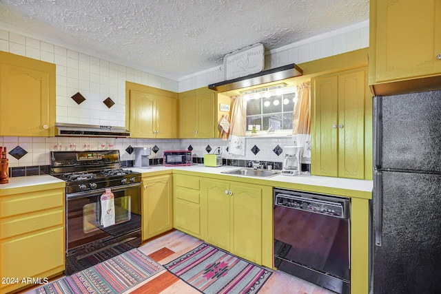 kitchen featuring a sink, a textured ceiling, black appliances, light countertops, and light wood-style floors