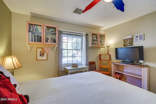 bedroom with ceiling fan, visible vents, and a textured ceiling