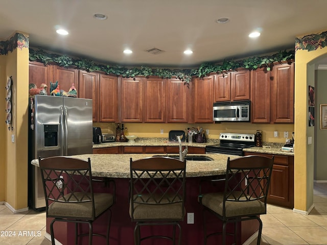 kitchen featuring a kitchen breakfast bar, sink, stainless steel appliances, and a kitchen island with sink