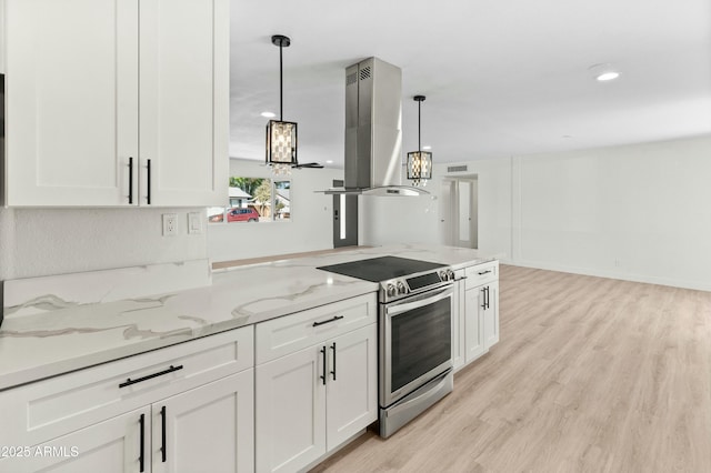 kitchen featuring light stone counters, decorative light fixtures, stainless steel electric range, island range hood, and white cabinets