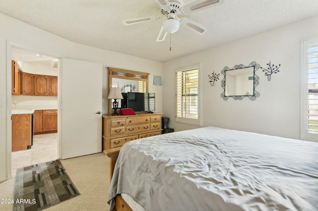 bedroom featuring a textured ceiling, ensuite bathroom, and ceiling fan