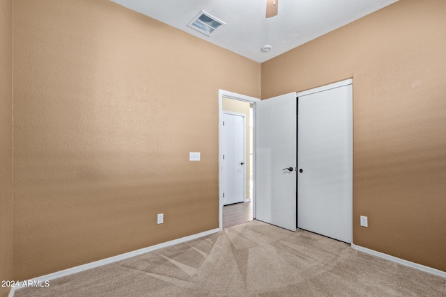 unfurnished bedroom featuring ceiling fan, light colored carpet, and a closet