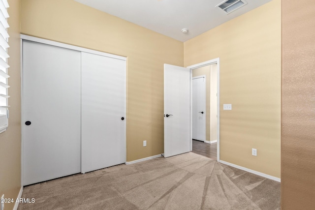 unfurnished bedroom with light carpet and a closet