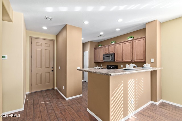 kitchen with dark wood-type flooring, range, and kitchen peninsula