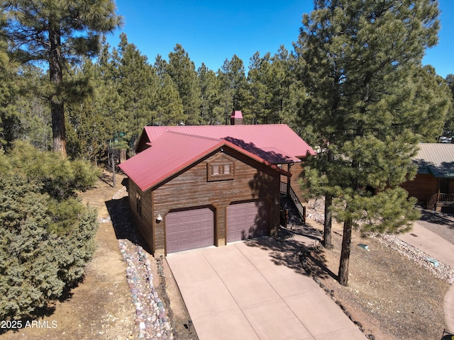 view of front of property with driveway, stairs, and metal roof