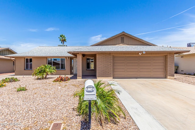 ranch-style home featuring brick siding, a shingled roof, an attached garage, and concrete driveway