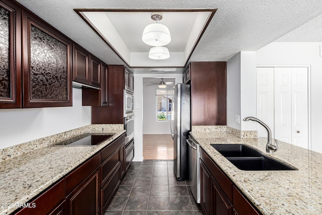 kitchen featuring a ceiling fan, light stone countertops, dark tile patterned flooring, a sink, and stainless steel appliances