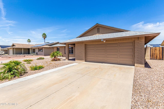 single story home featuring solar panels, brick siding, fence, concrete driveway, and an attached garage