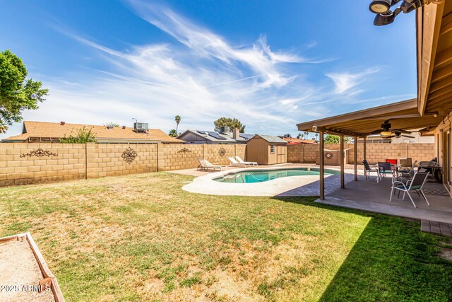 view of yard with an outdoor structure, a fenced backyard, a storage unit, a ceiling fan, and a patio area