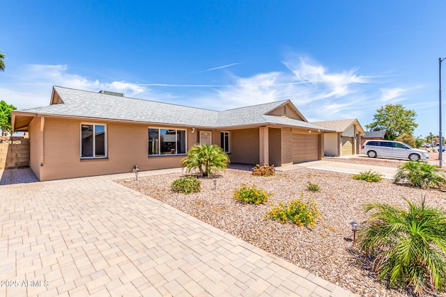 ranch-style house with driveway, roof with shingles, and a garage