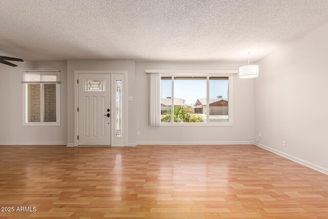 entrance foyer with baseboards, a textured ceiling, ceiling fan, and light wood finished floors