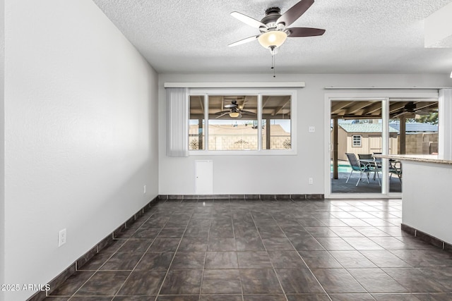 unfurnished room featuring baseboards, a ceiling fan, a textured ceiling, and a healthy amount of sunlight