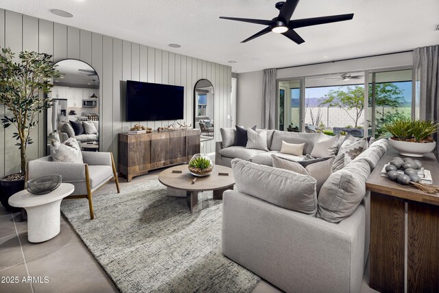 living room with a textured ceiling, ceiling fan, and wood walls