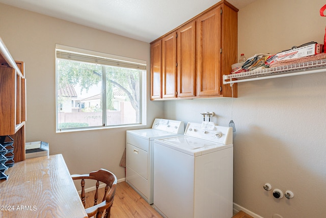 washroom with cabinets, washing machine and dryer, and light hardwood / wood-style floors