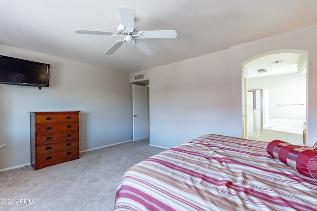 bedroom with light carpet, ceiling fan, and ensuite bath