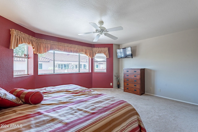 bedroom featuring multiple windows, ceiling fan, light colored carpet, and a textured ceiling