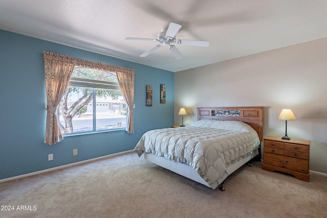 bedroom with ceiling fan, light colored carpet, and a textured ceiling