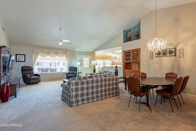 carpeted living room featuring ceiling fan with notable chandelier and high vaulted ceiling