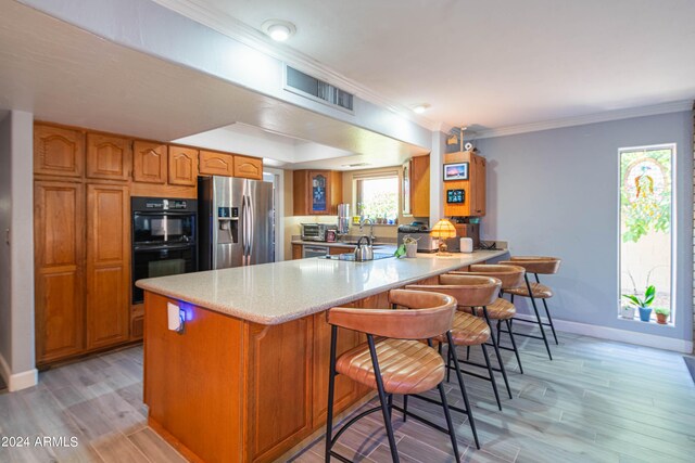 kitchen featuring a wealth of natural light, a breakfast bar, kitchen peninsula, and stainless steel fridge with ice dispenser