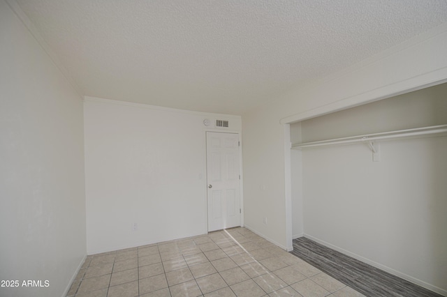 2846 N 46th Ave Unit 7, Phoenix, AZ 85035 - unfurnished bedroom with a textured ceiling, a closet, and light tile patterned floors