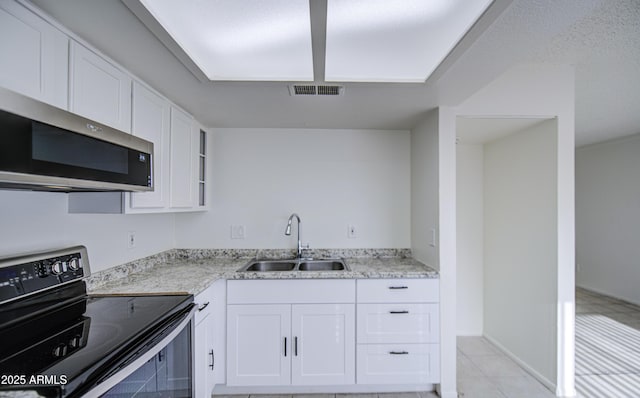 2846 N 46th Ave Unit 7, Phoenix, AZ 85035 - kitchen featuring range with electric stovetop, a sink, stainless steel microwave, white cabinetry, and light tile patterned flooring