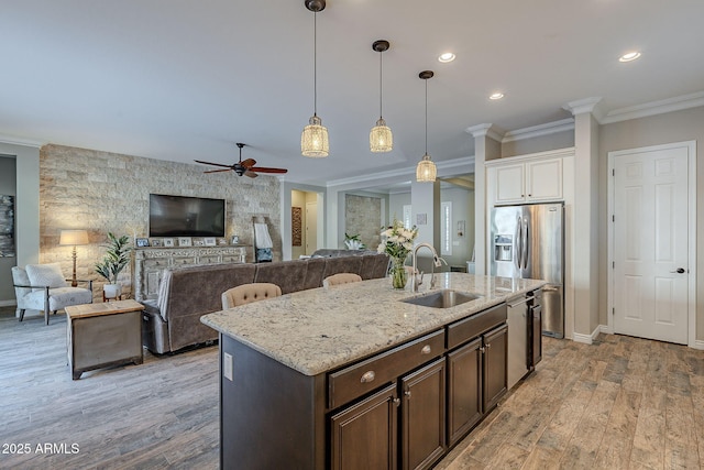 kitchen with an island with sink, sink, white cabinets, ornamental molding, and dark brown cabinetry